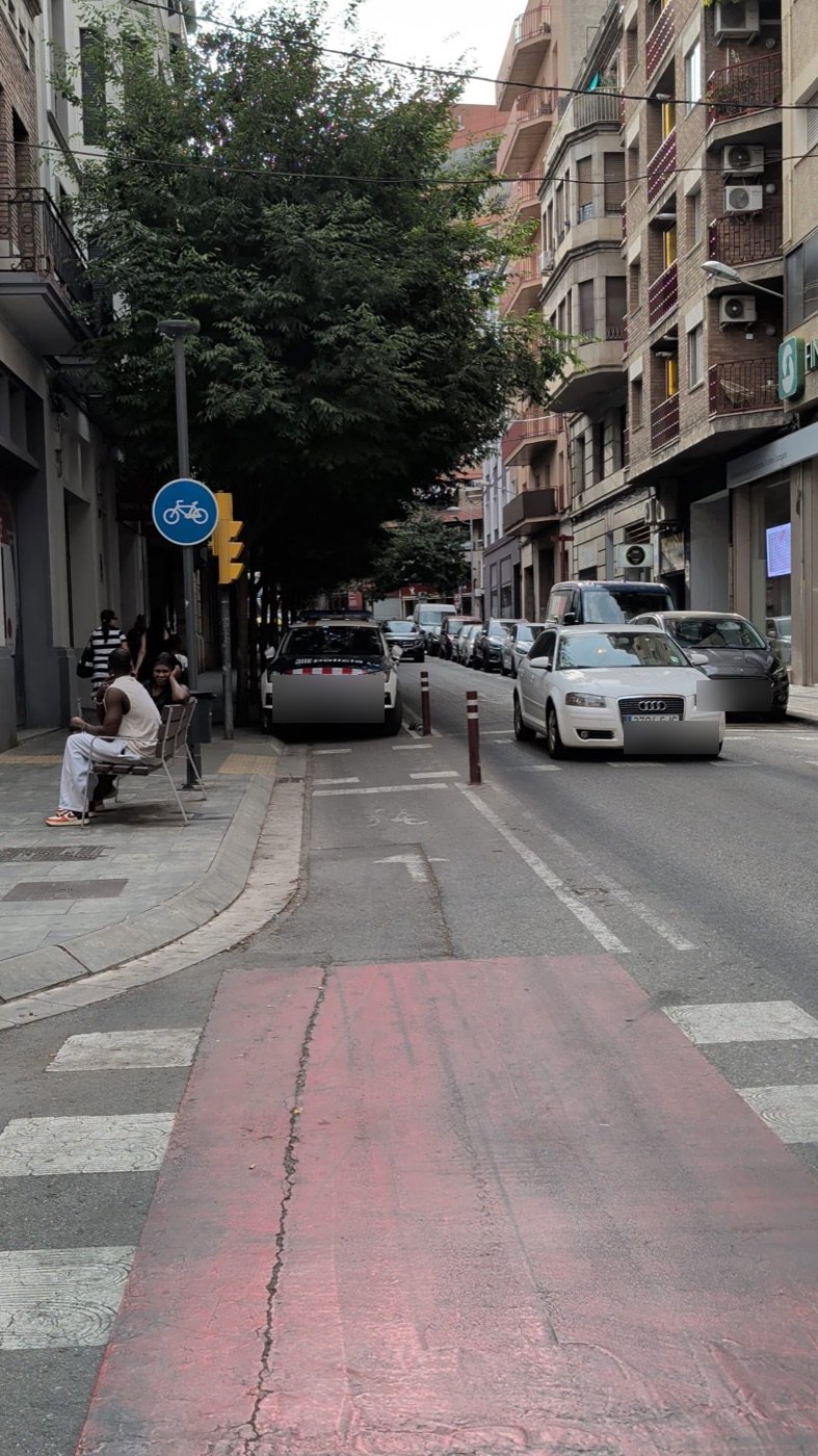 Vehicles aturats sobre el carril bici en un carrer de Lleida amb senyal de carril bici.